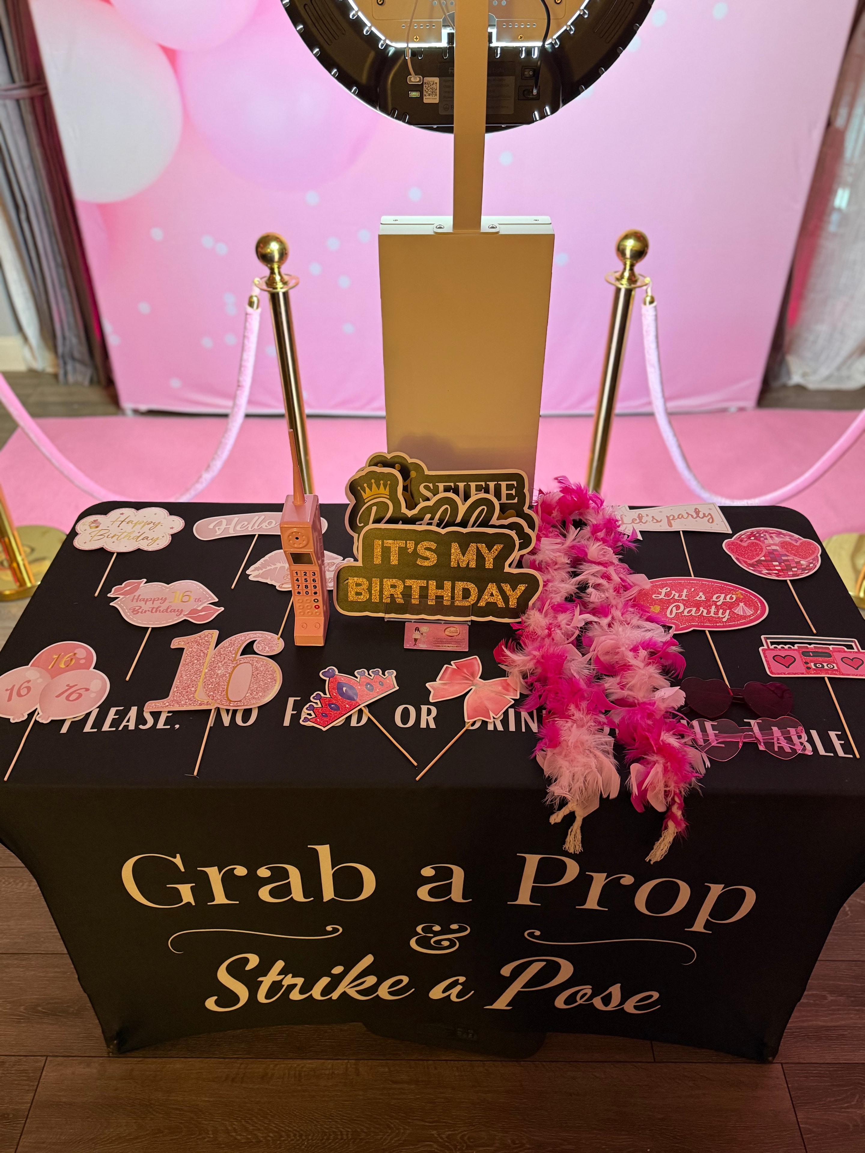 Birthday photo booth prop table with pink balloon backdrop